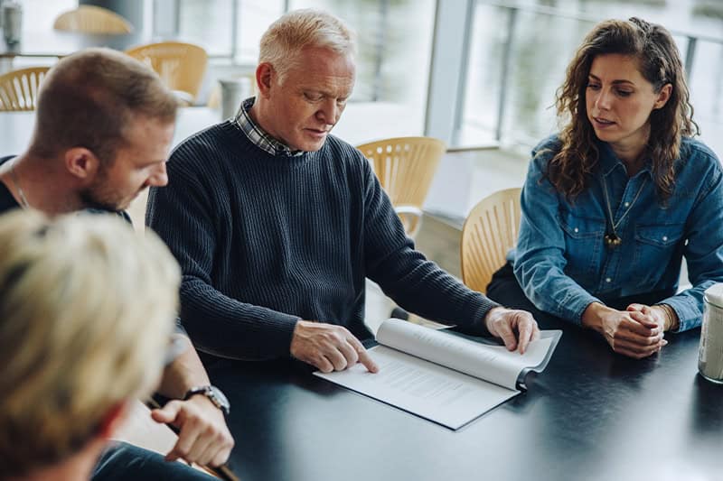 Chef kommunikerer og giver positiv feedback til tre medarbejdere på arbejdspladsen.
